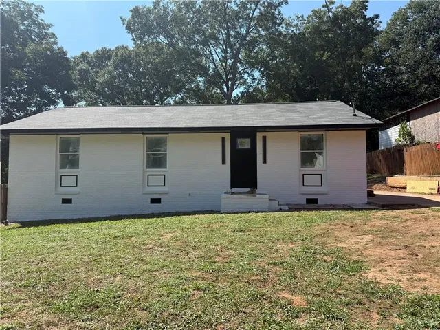 a house that is sitting in the grass next to a yard