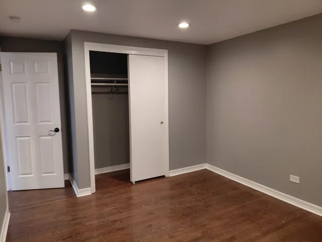 a view of an empty room with wooden floor and closet