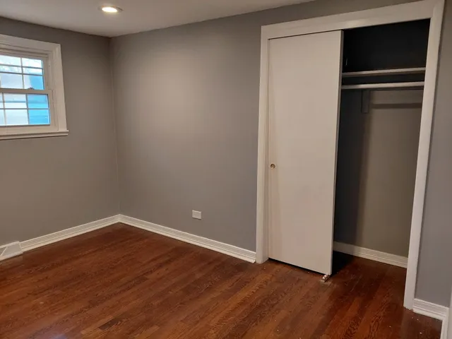a view of an empty room with wooden floor and closet