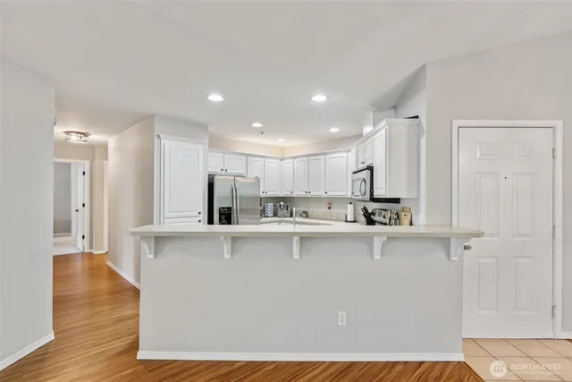 a view of a kitchen with kitchen island white cabinetry and wooden floor
