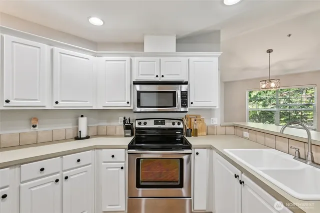 a kitchen with granite countertop a sink stainless steel appliances and cabinets