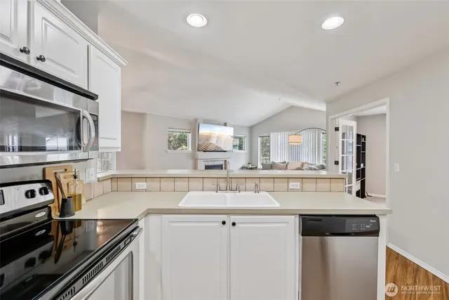 a kitchen with kitchen island granite countertop a sink cabinets and stainless steel appliances