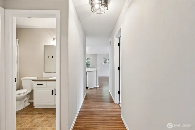 a view of a hallway with bathroom and wooden floor
