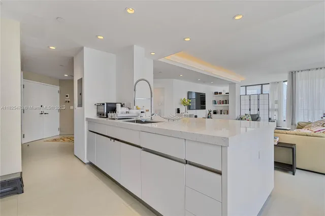 a large white kitchen with kitchen island a sink a stove and a refrigerator