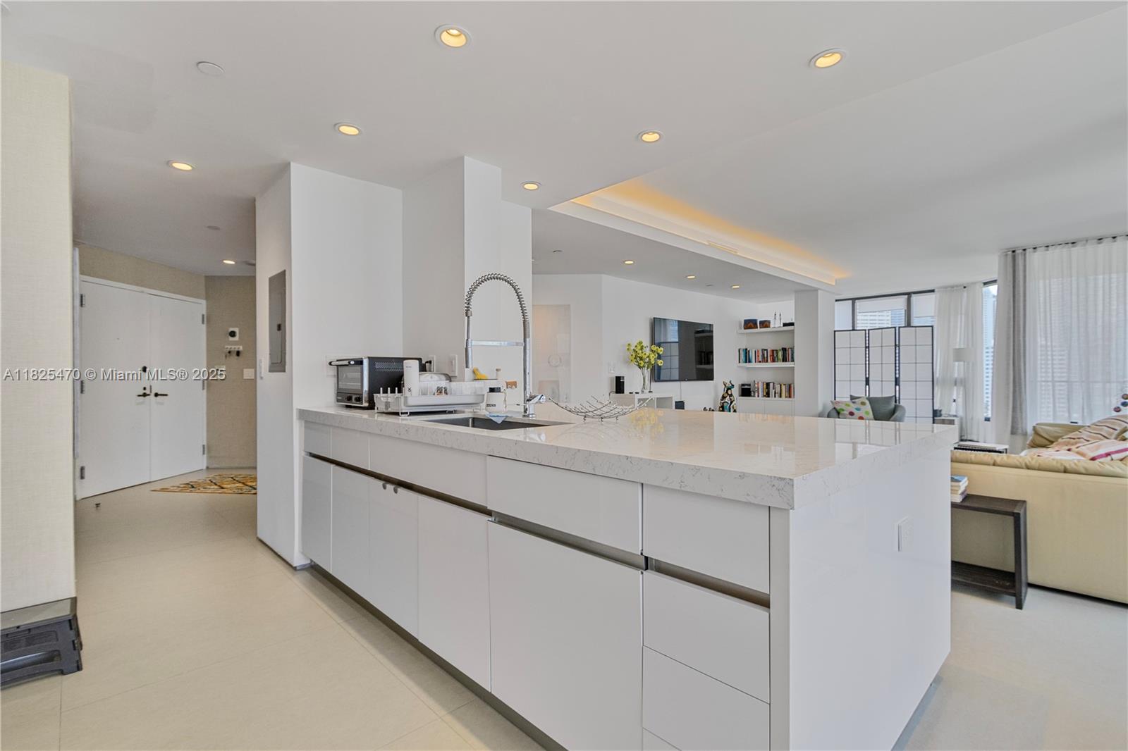 a large white kitchen with kitchen island a sink a stove and a refrigerator