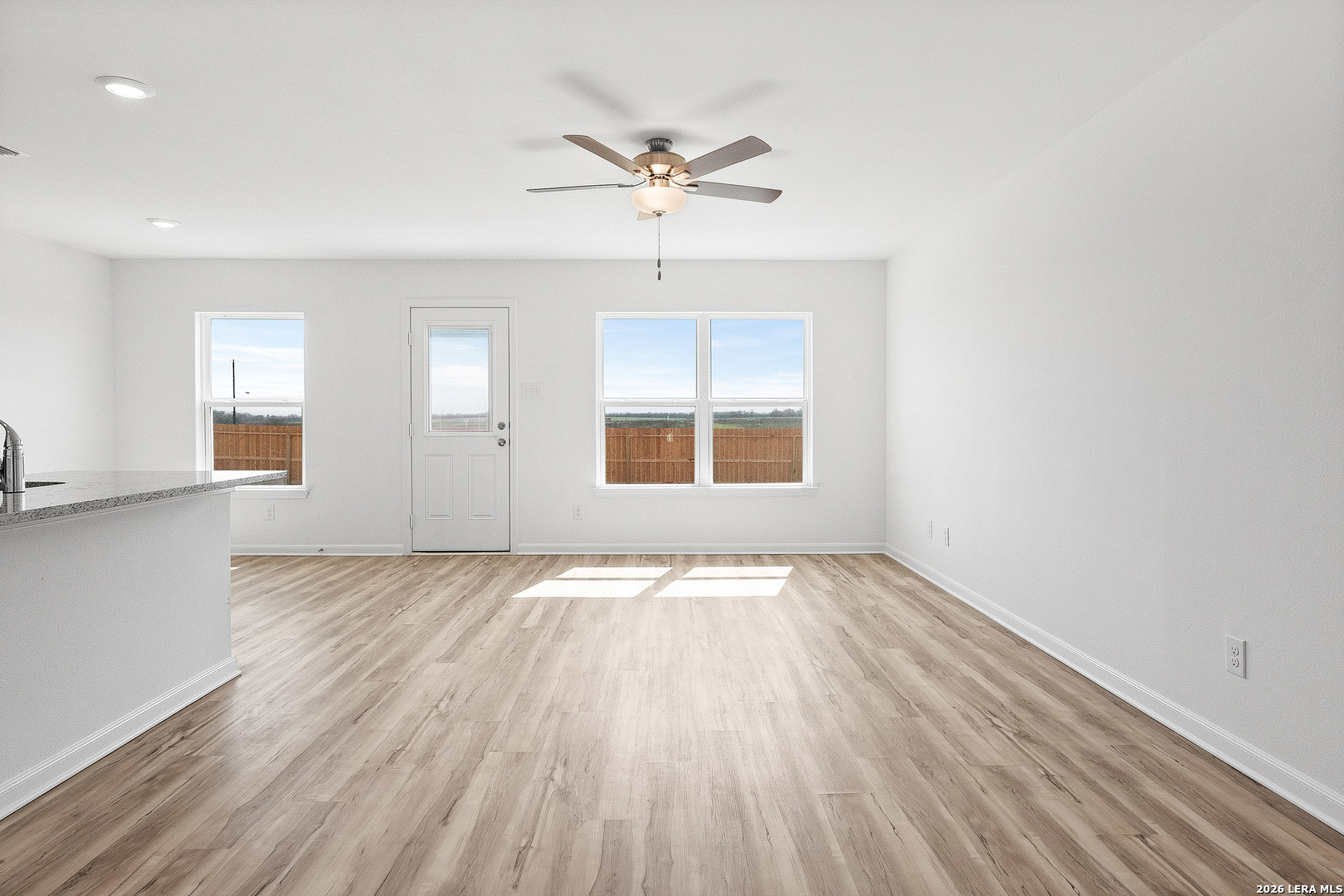 16189 Farmer Lytle, TX 78052 - Photo 7 of 28 an empty room with wooden floor chandelier fan and windows