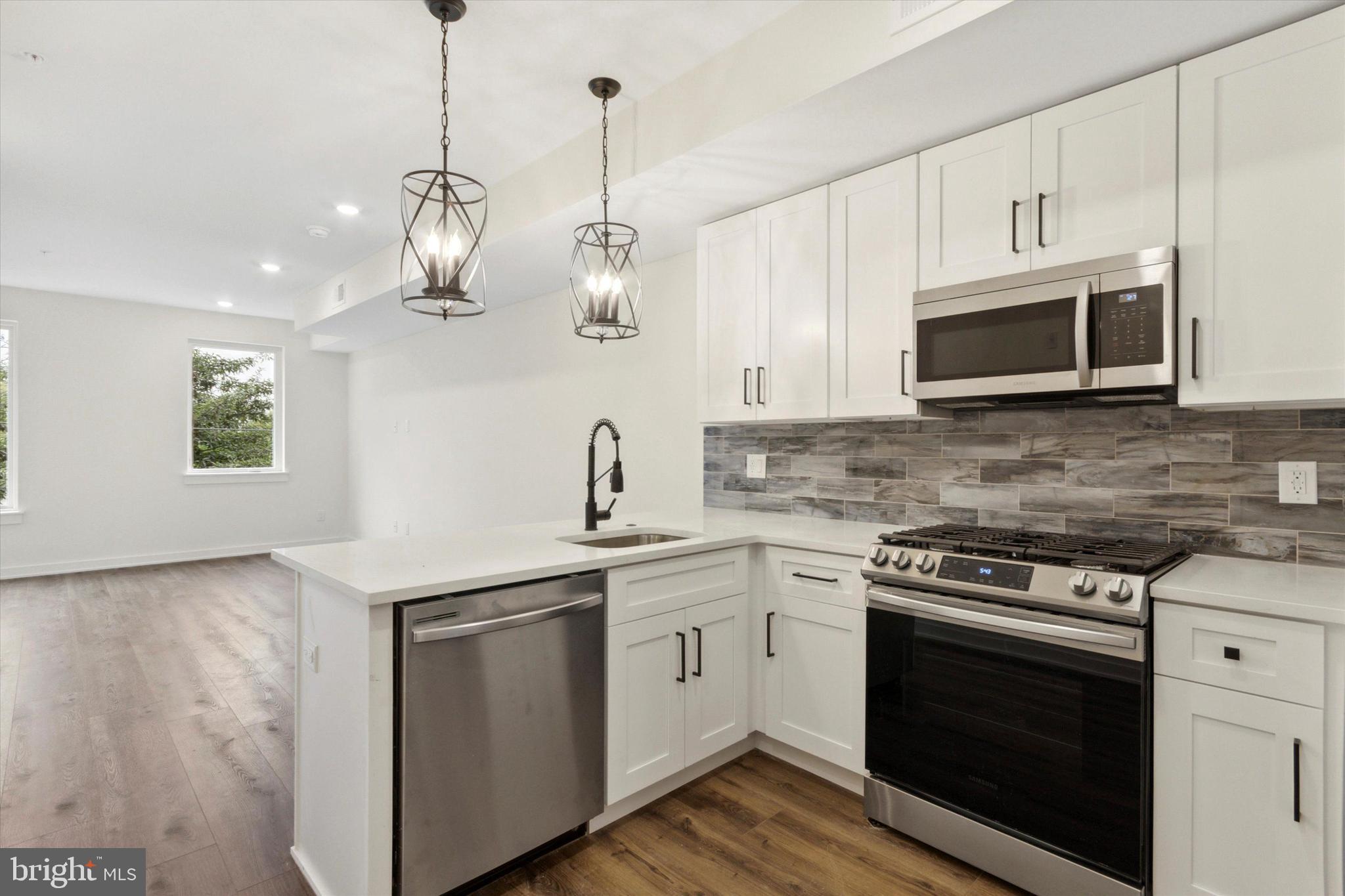 1826 Frankford Avenue, Unit 3 Philadelphia, PA 19125 - Photo 1 of 18 a kitchen with stainless steel appliances granite countertop a sink a stove a microwave and wooden cabinets