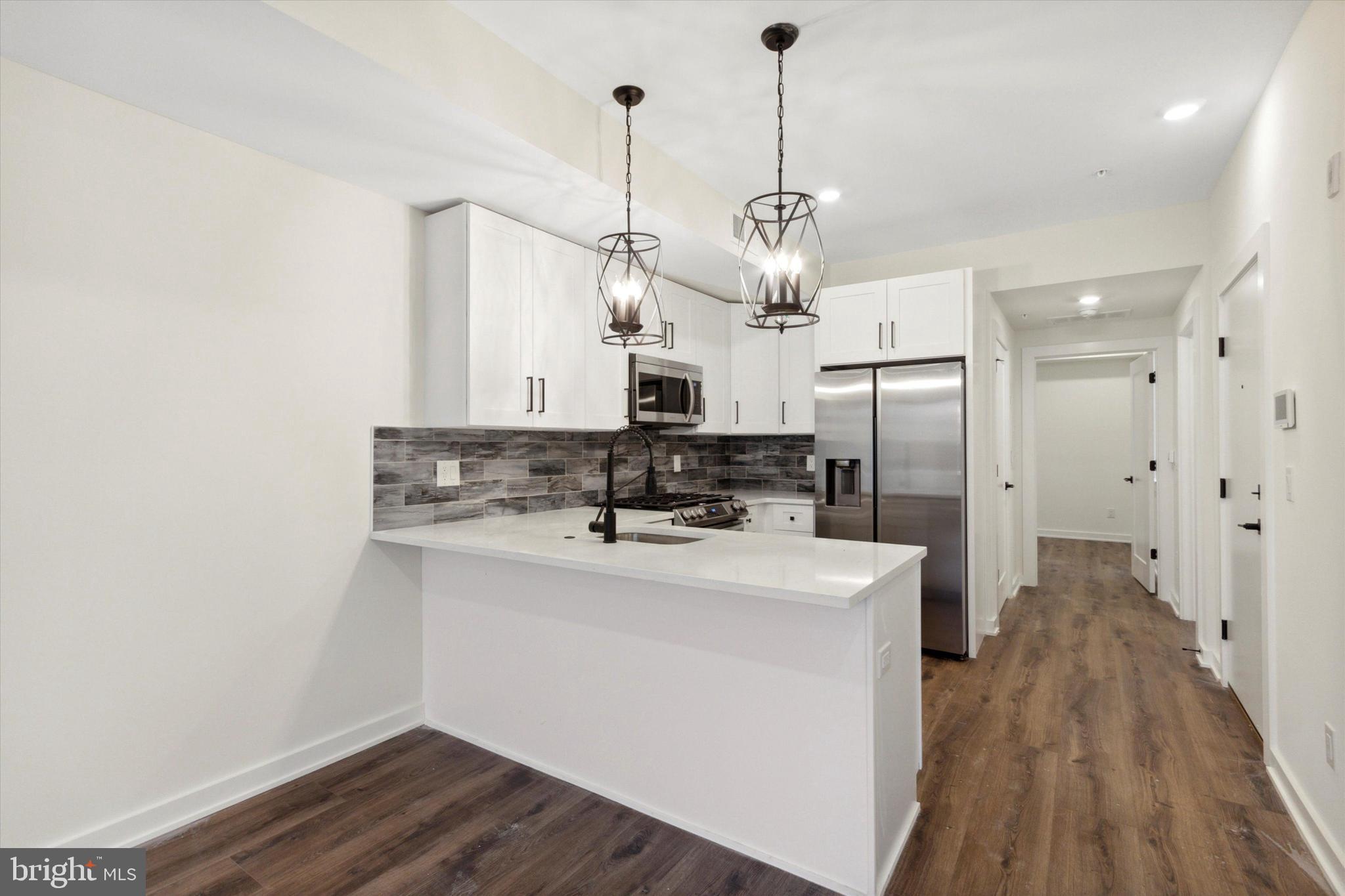 1826 Frankford Avenue, Unit 3 Philadelphia, PA 19125 - Photo 2 of 18 a kitchen with stainless steel appliances a refrigerator a sink dishwasher a stove and white cabinets with wooden floor