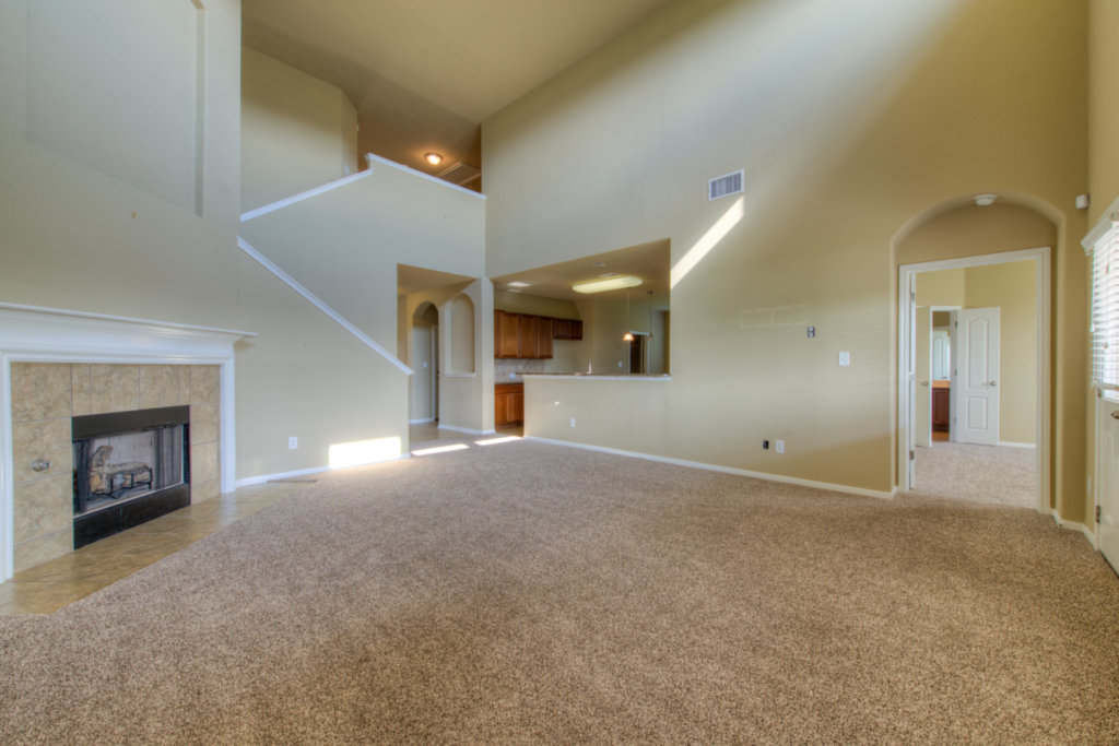 403 Limestone Trail Austin, TX 78737 - Photo 8 of 18 A spacious living area with soaring ceilings and a cozy fireplace, seamlessly connecting to the kitchen.