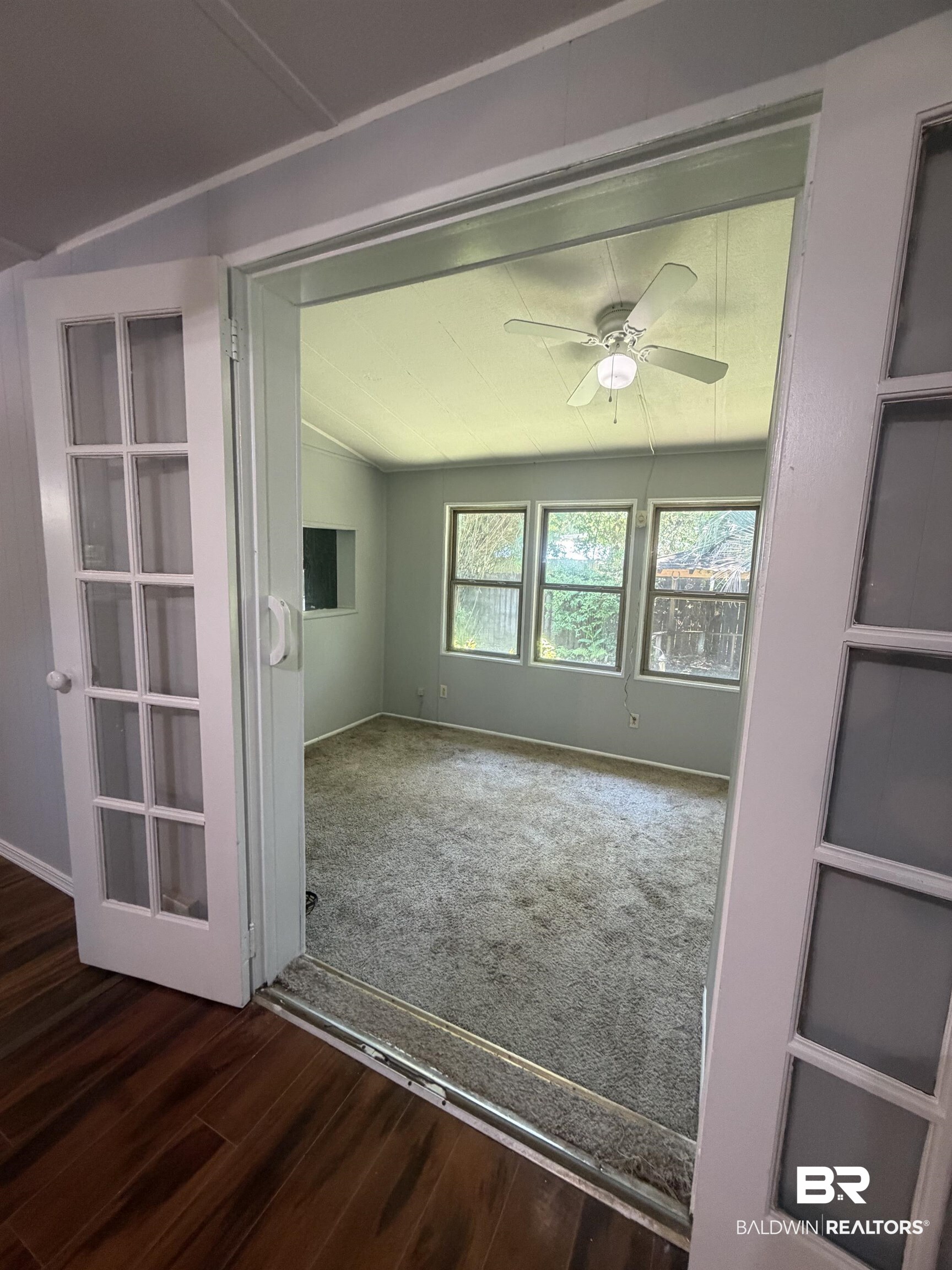 1354 Caney Loop Lillian, AL 36549 - Photo 12 of 45 French doors opening to a room featuring multiple windows, a ceiling fan with integrated lighting, and carpet flooring