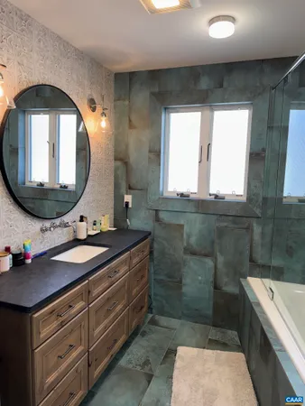 a bathroom with a granite countertop sink a mirror and a bathtub