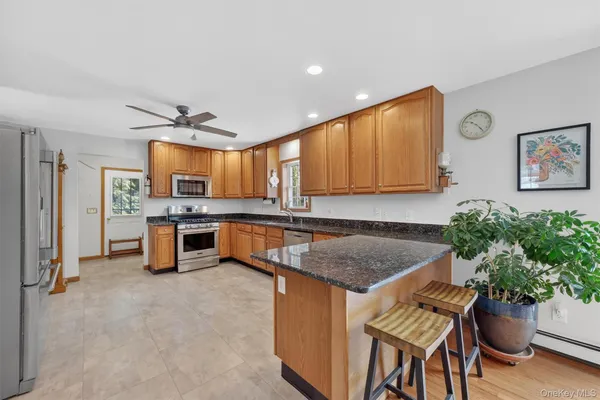 a kitchen with stainless steel appliances granite countertop a refrigerator a sink a stove and chairs