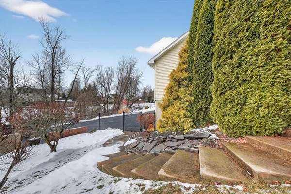 a front view of a house with a yard covered with snow and trees