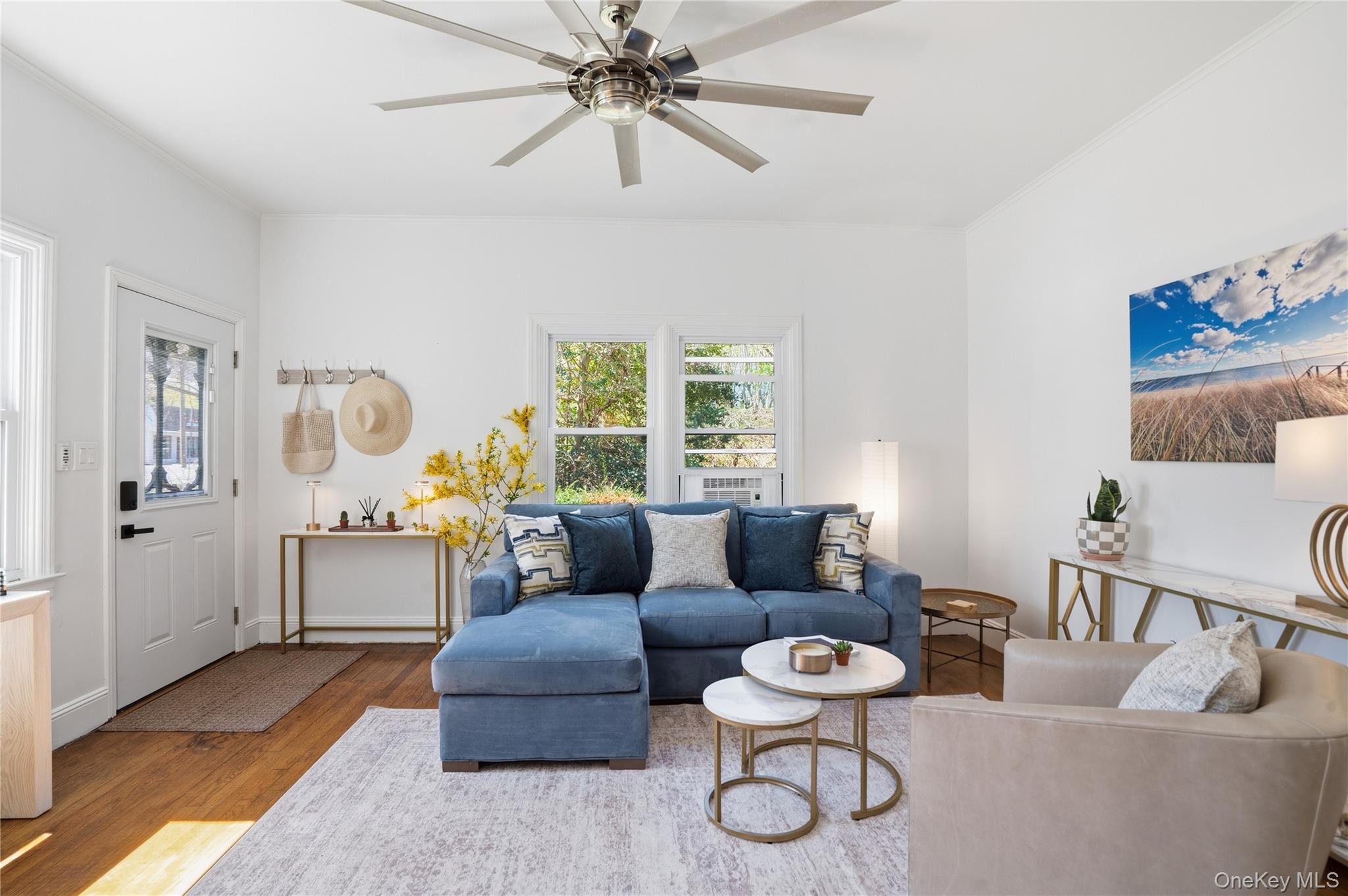 1550 Main Road Riverhead, NY 11901 - Photo 4 of 28 Living area featuring wood-finish flooring, a contemporary ceiling fan, and multiple windows providing natural light