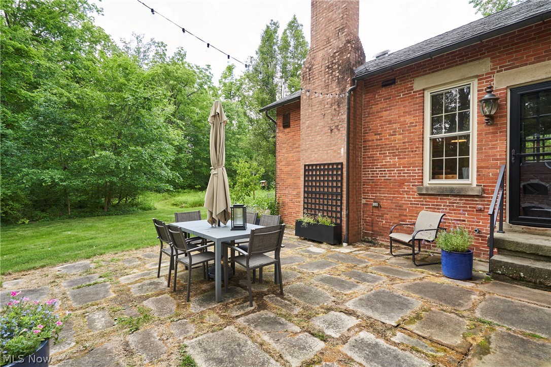 5046 Alger Road Richfield, OH 44286 - Photo 43 of 49 Stone patio featuring a red brick exterior, large window with white trim, and a black wrought iron railing