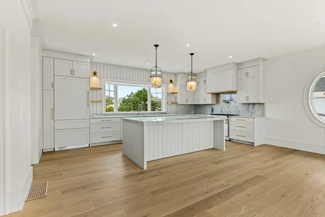 a kitchen with stainless steel appliances kitchen island granite countertop a stove a sink and white cabinets