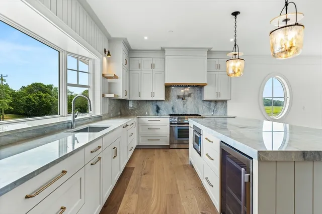 a large kitchen with stainless steel appliances granite countertop a stove a sink and a wooden floors