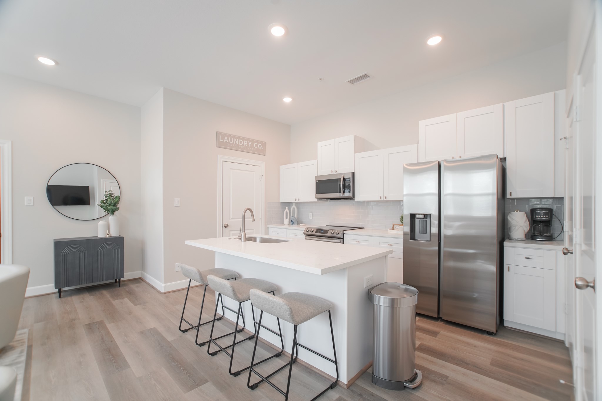 504 Nursery Road, Unit 3206 The Woodlands, TX 77380 - Photo 16 of 35 a kitchen with stainless steel appliances a refrigerator a stove a sink a dining table and chairs with wooden floor