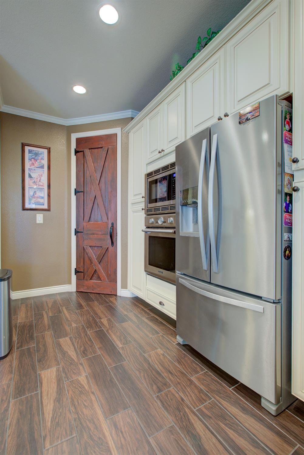 621 Bouma Lane Ripon, CA 95366 - Photo 23 of 78 a view of a refrigerator in kitchen and an empty room with wooden floor
