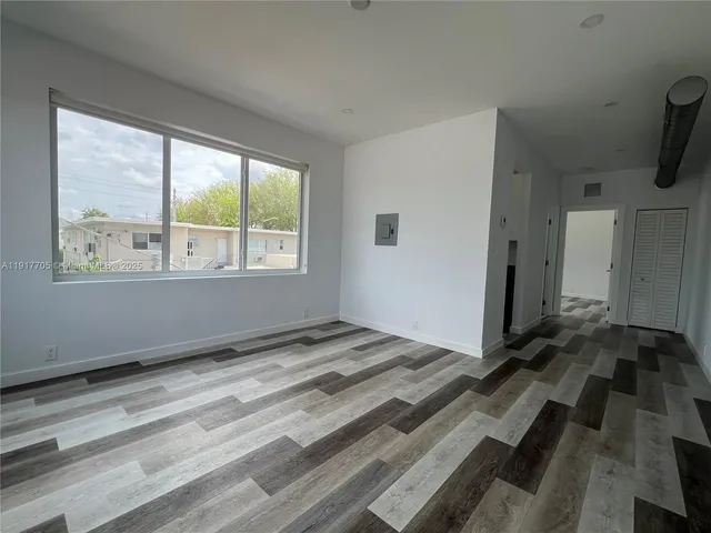 a view of a bedroom with wooden floor and a window