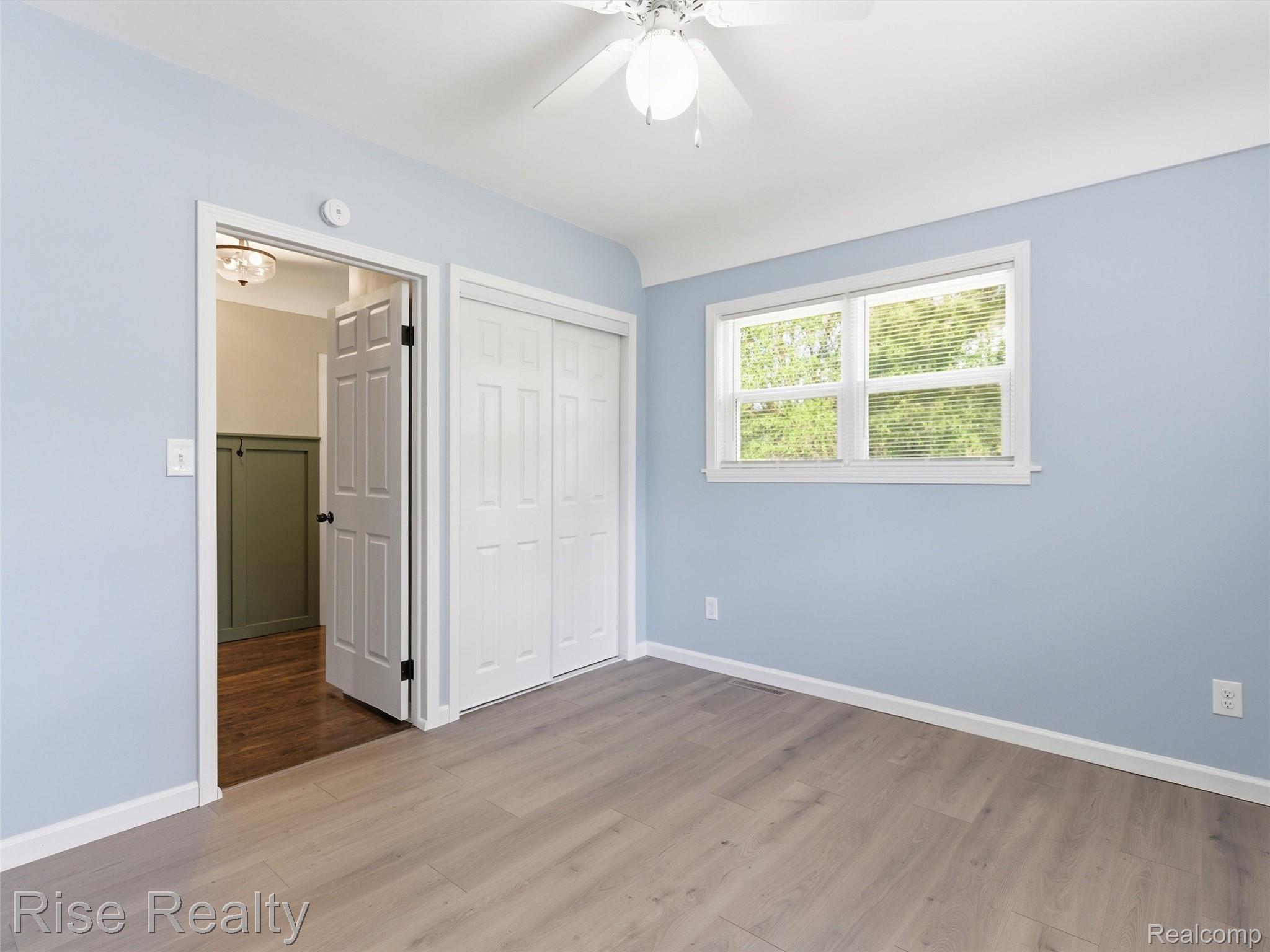 2449 North Genesee Road Burton, MI 48509 - Photo 15 of 40 Room featuring light blue walls, wood-finish flooring, a white bi-fold closet, and a ceiling fan with light fixture