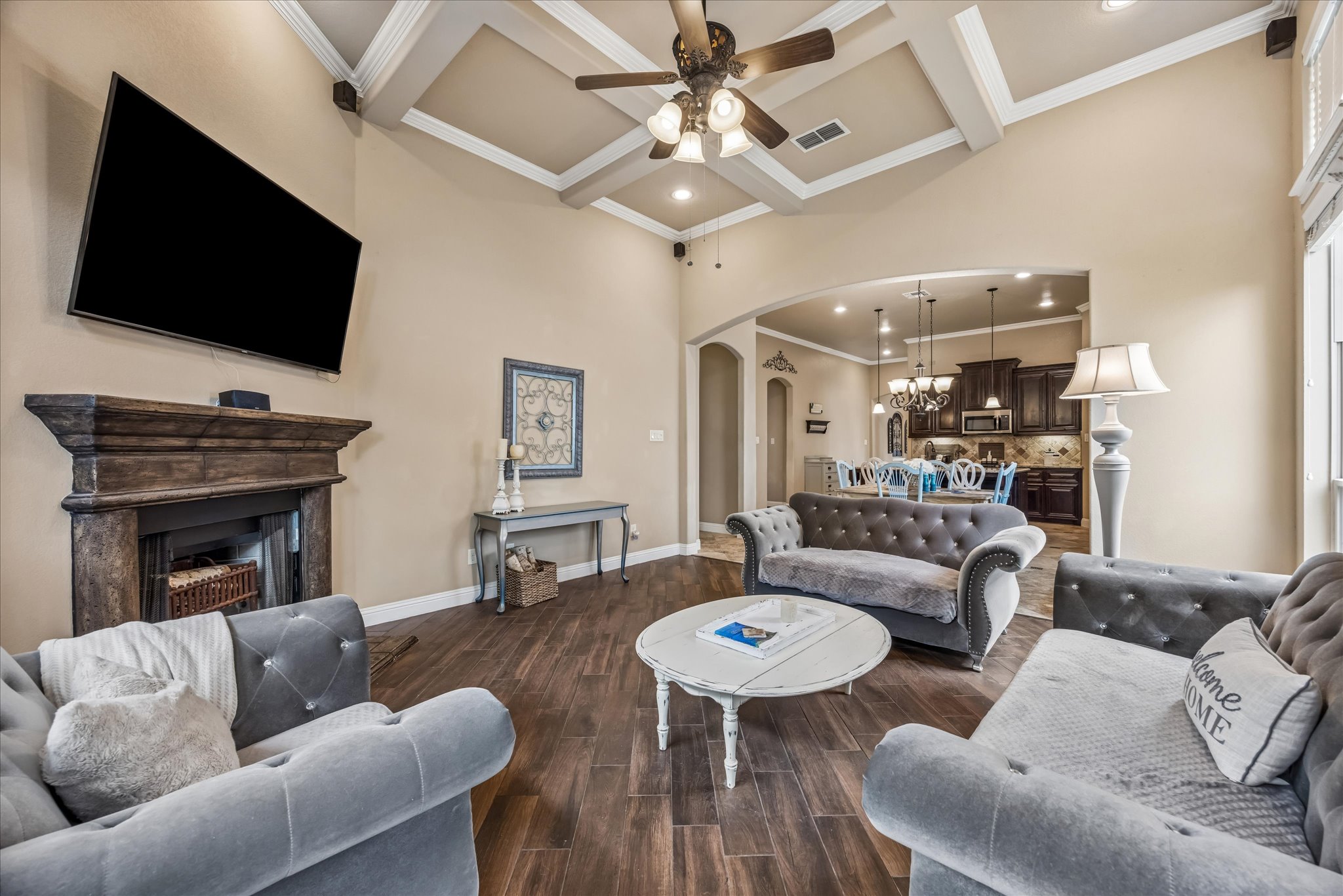 108 Rhinestone Cove Liberty Hill, TX 78642 - Photo 12 of 32 Living area featuring a coffered ceiling with a ceiling fan, a fireplace with a wood-finish mantel, and wood-finish flooring