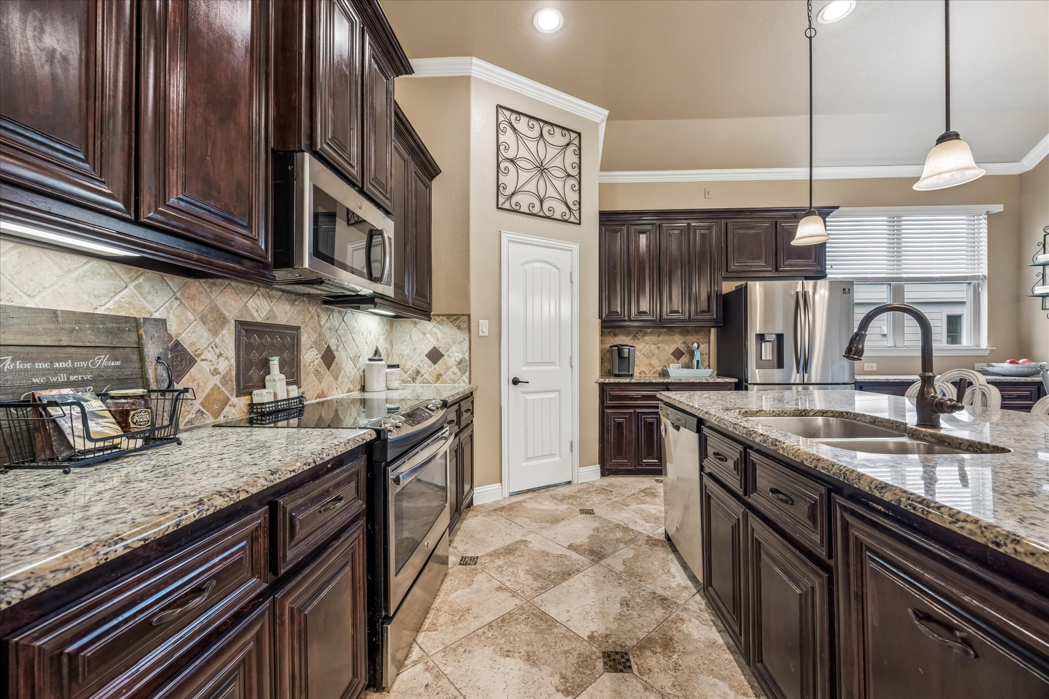 108 Rhinestone Cove Liberty Hill, TX 78642 - Photo 14 of 32 Kitchen featuring a large island with an undermount sink and gooseneck faucet, granite countertops, dark wood cabinetry, stainless steel appliances, and a tiled backsplash