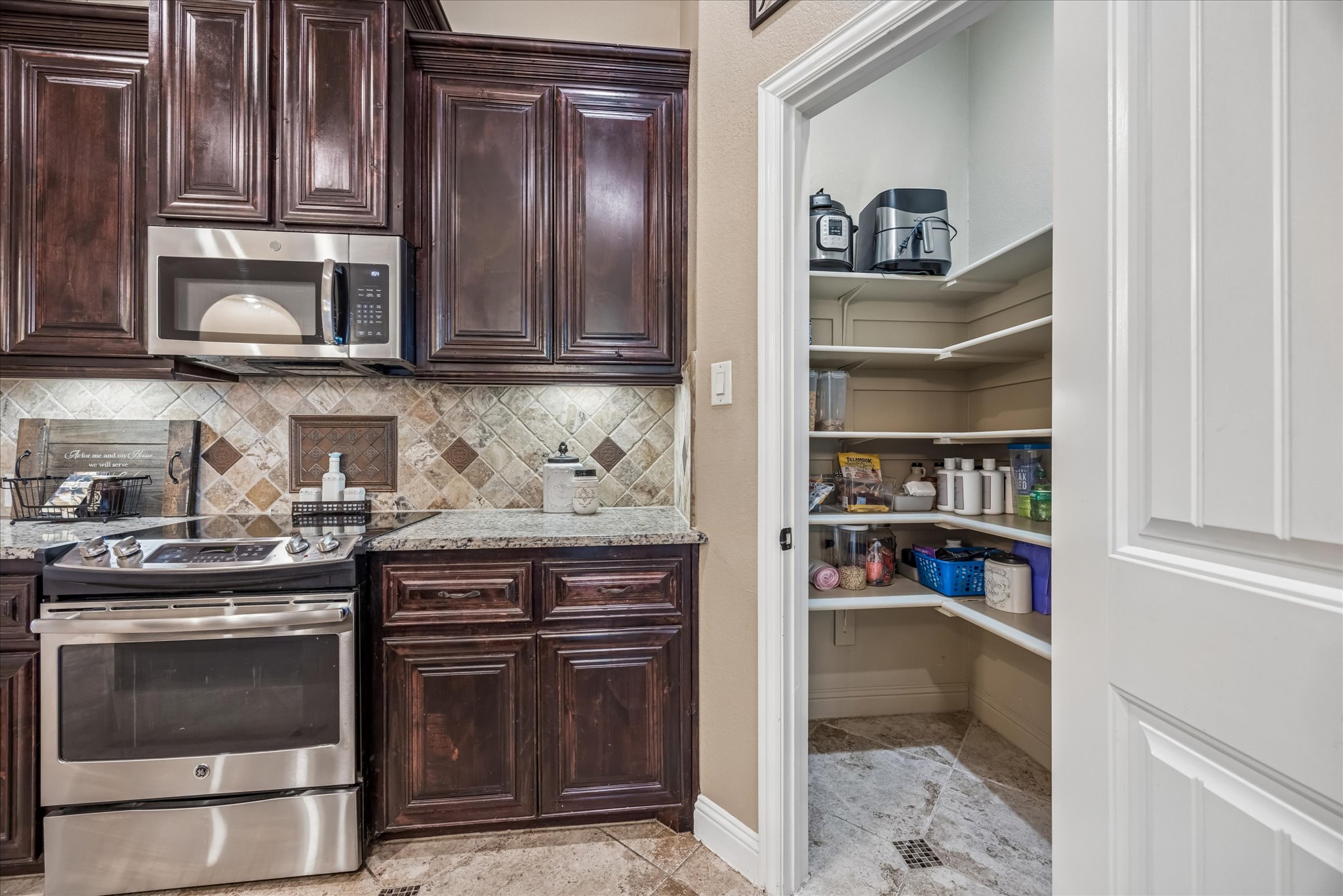 108 Rhinestone Cove Liberty Hill, TX 78642 - Photo 15 of 32 Kitchen with dark wood cabinetry, stainless steel appliances, granite-style countertops, and a tile backsplash