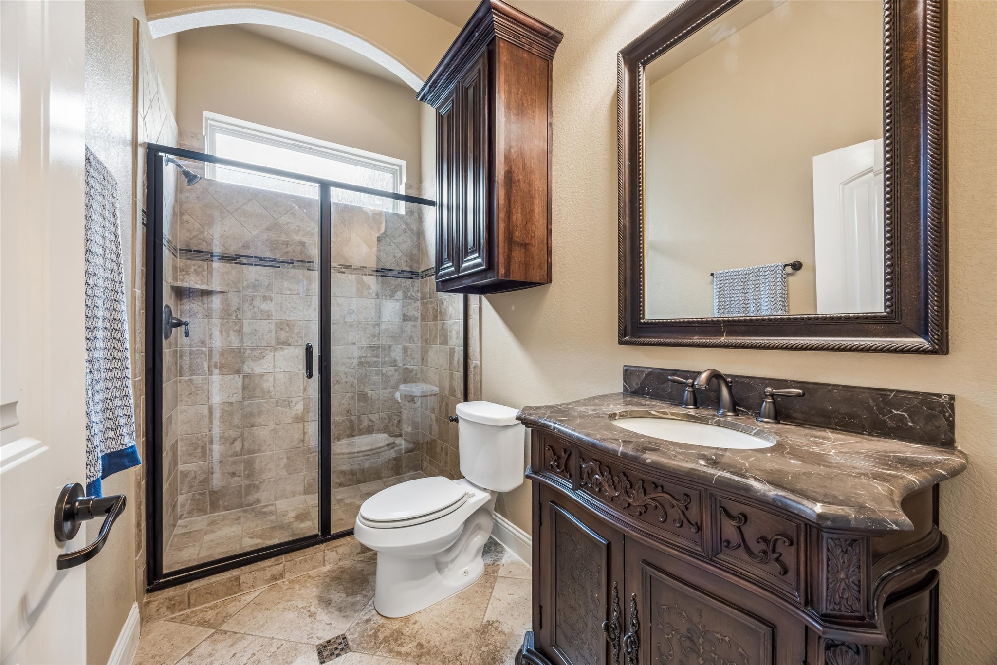 108 Rhinestone Cove Liberty Hill, TX 78642 - Photo 24 of 32 Bathroom featuring a frameless glass shower enclosure, a single vanity with an integrated sink, dark vanity cabinetry, a dark framed mirror, and a wall-mounted wood-finish cabinet