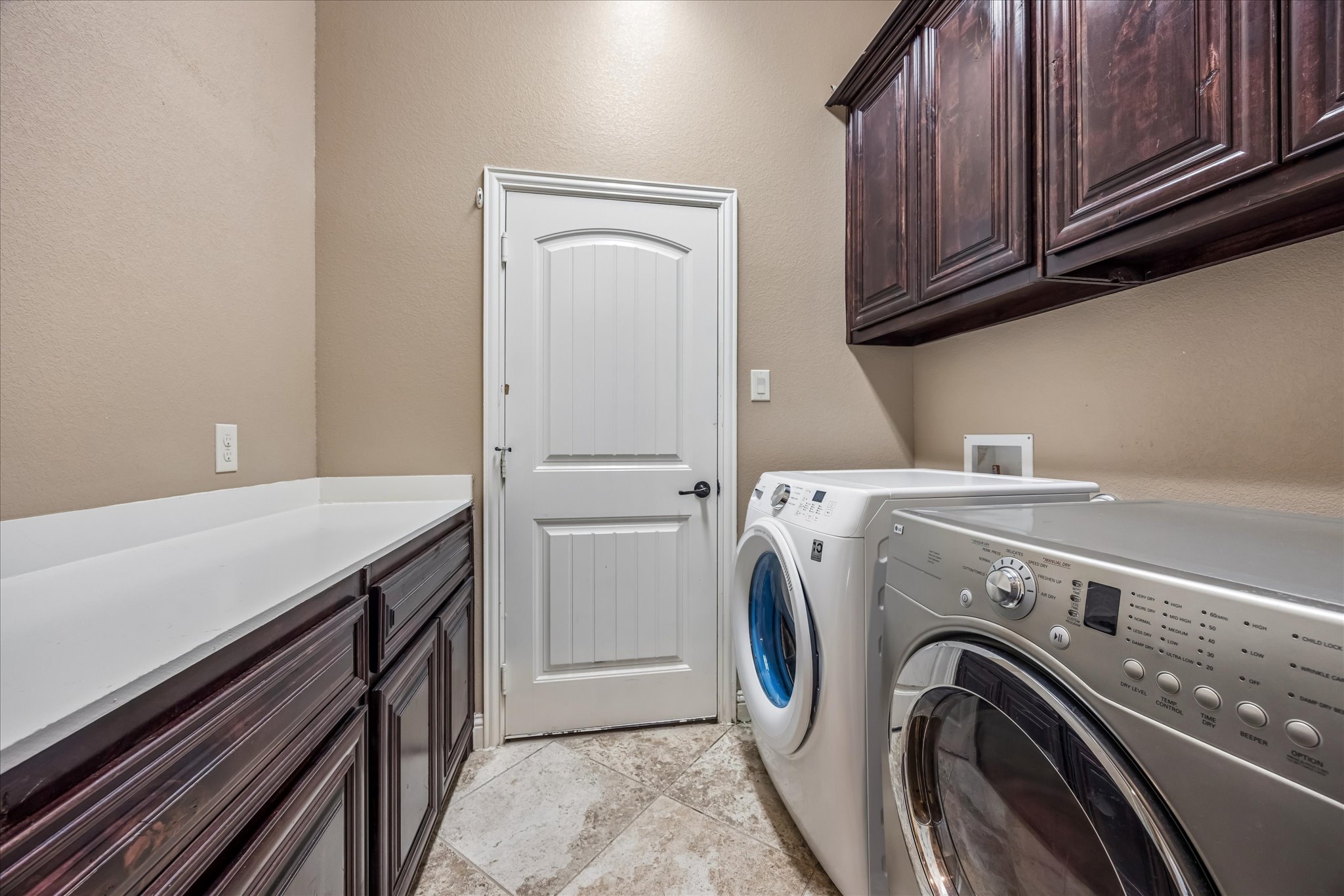 108 Rhinestone Cove Liberty Hill, TX 78642 - Photo 26 of 32 Dedicated laundry area featuring dark wood-finish cabinetry, white solid-surface countertops, and tile flooring