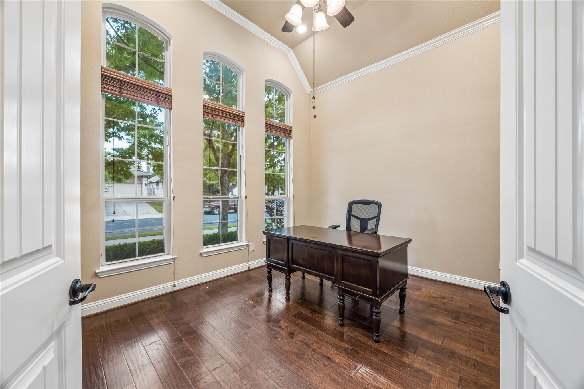 108 Rhinestone Cove Liberty Hill, TX 78642 - Photo 7 of 32 Bright room featuring three arched windows with horizontal blinds, dark wood-finish flooring, and a vaulted ceiling with a flush-mount light fixture