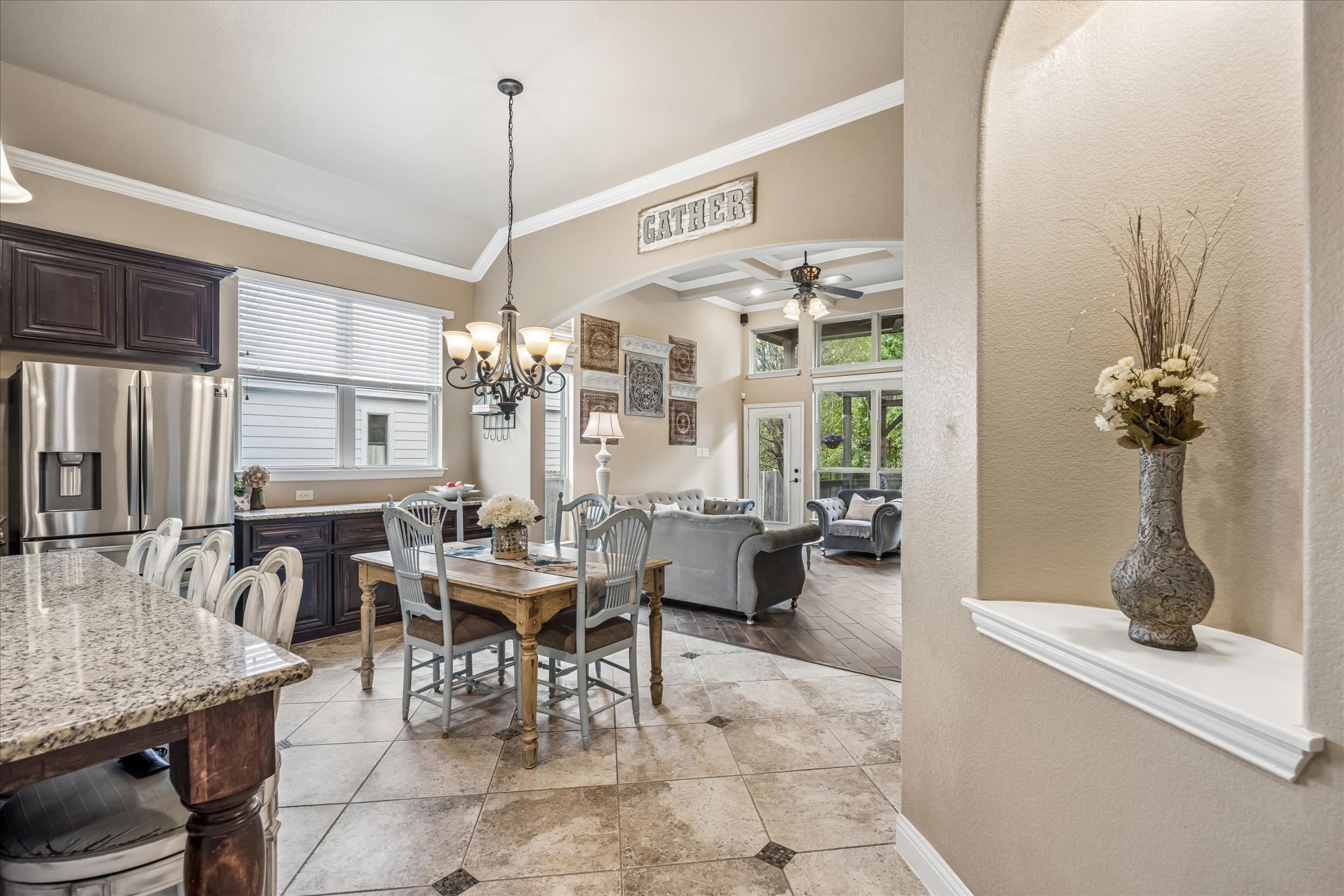 108 Rhinestone Cove Liberty Hill, TX 78642 - Photo 9 of 32 Open-concept kitchen and dining area featuring tile flooring, dark wood-finish cabinetry, stainless steel refrigerator, and a kitchen island with a granite-style countertop