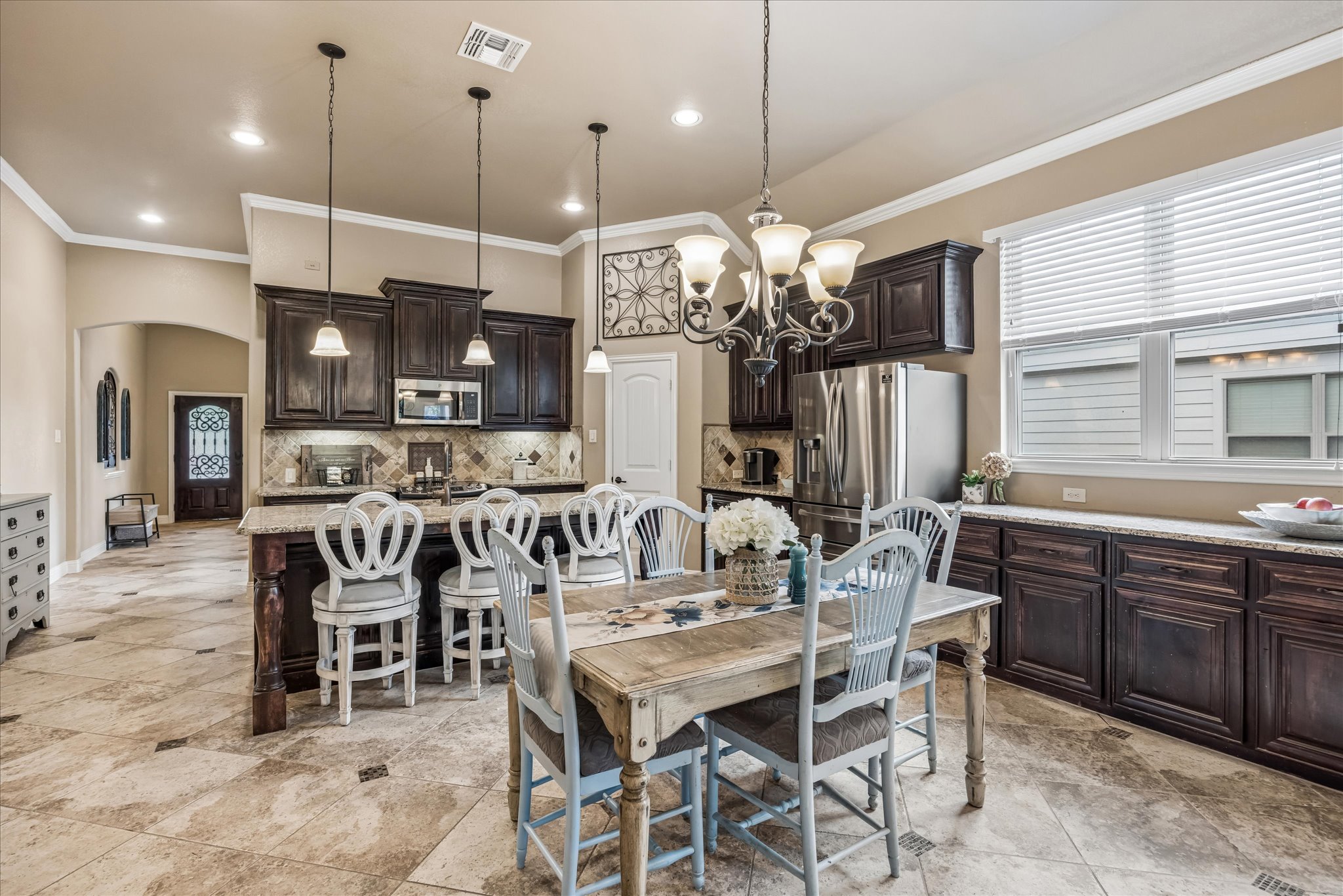 108 Rhinestone Cove Liberty Hill, TX 78642 - Photo 10 of 32 Spacious kitchen featuring dark wood cabinetry, a central island with bar seating, stainless steel appliances, and a tiled backsplash