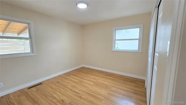 an empty room with wooden floor and windows
