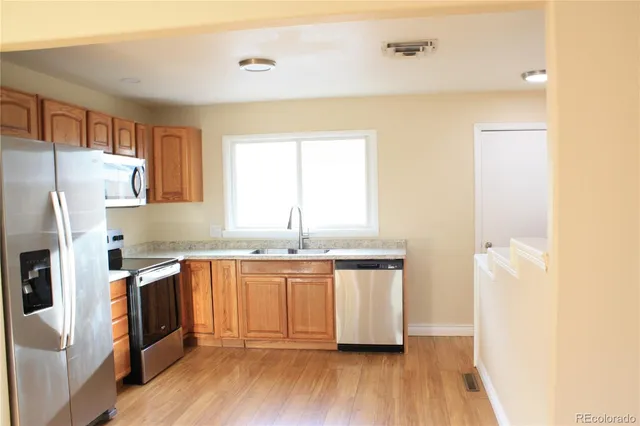 a kitchen with granite countertop a sink a counter space and stainless steel appliances