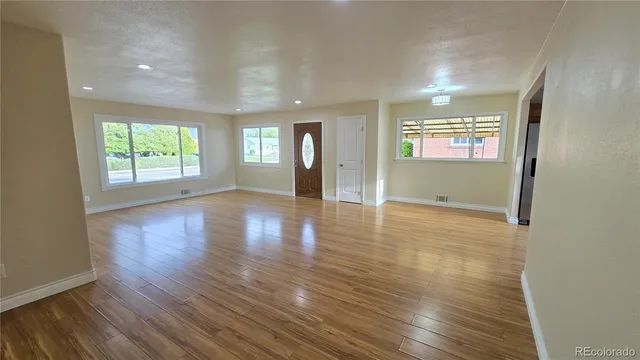 an empty room with wooden floor and windows