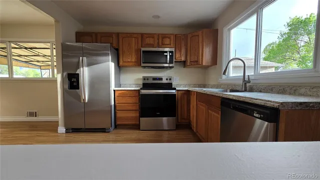 a kitchen with stainless steel appliances granite countertop a refrigerator a sink a stove a microwave and wooden cabinets