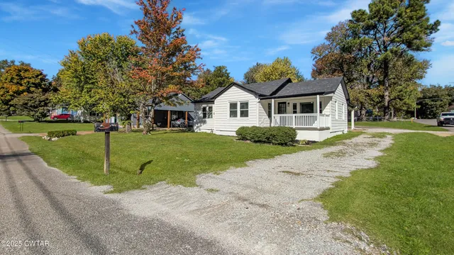 a view of a house with a big yard and large trees
