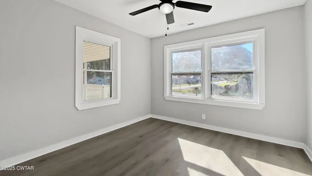 a view of an empty room with a window and wooden floor