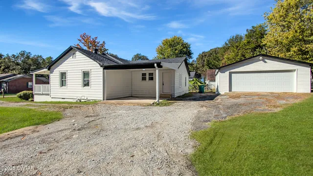 a view of a house with a yard and large tree