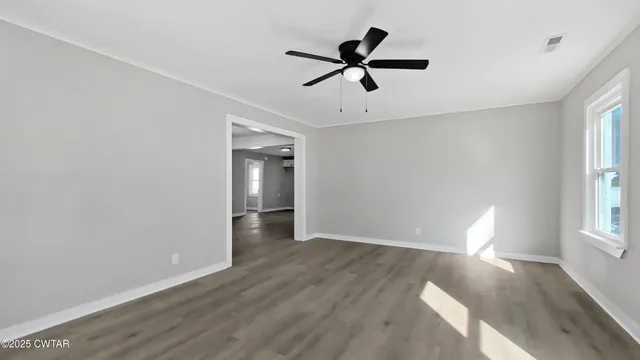 a view of empty room with wooden floor and fan