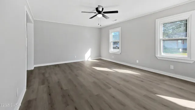 an empty room with windows and fan