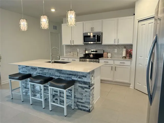 a kitchen with stainless steel appliances a stove a sink refrigerator and microwave
