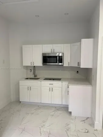 a kitchen with granite countertop white cabinets and stainless steel appliances