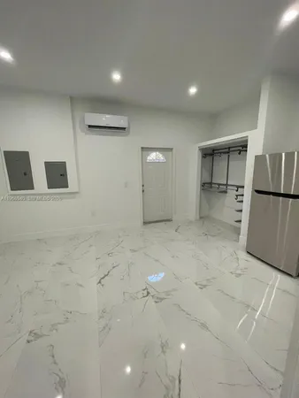 a view of a refrigerator in kitchen and an empty room