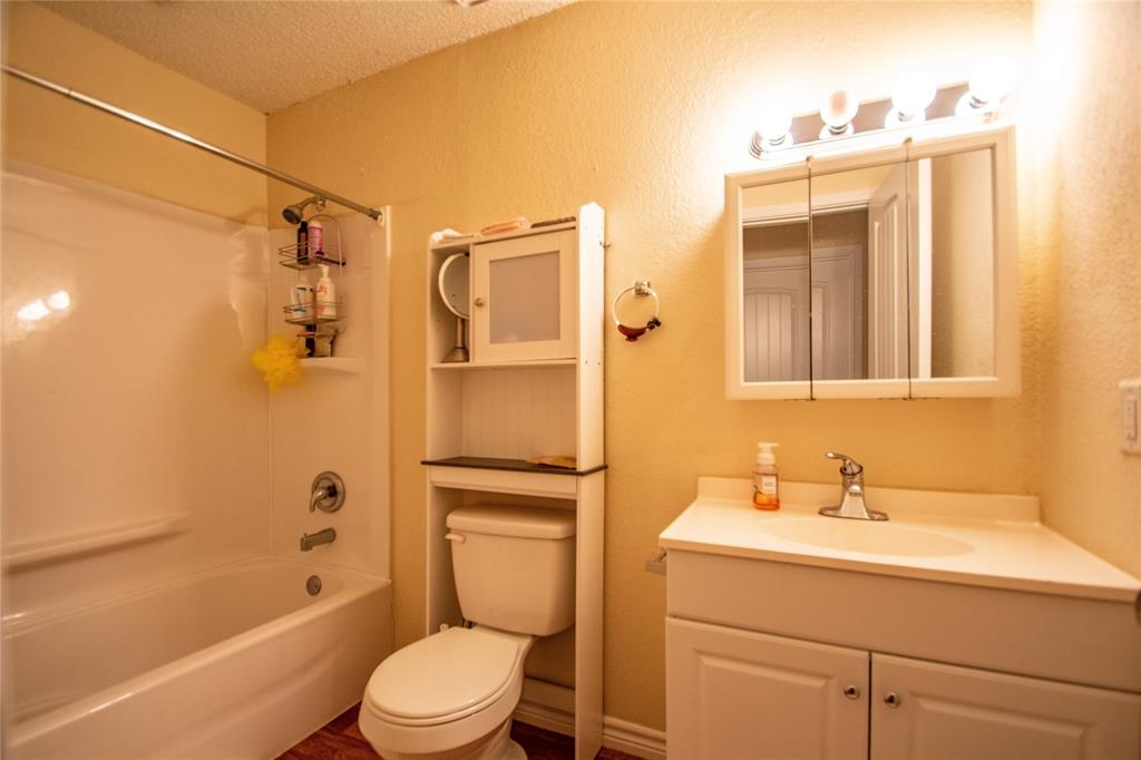 1817 Lipscomb Street Fort Worth, TX 76110 - Photo 6 of 10 Full bathroom featuring washtub / shower combination, vanity, toilet, and a textured ceiling