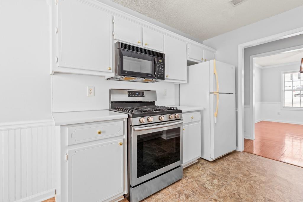 1707 Mountain Fort Way Dacula, GA 30019 - Photo 13 of 34 a kitchen with stainless steel appliances white cabinets white stove a microwave and a refrigerator