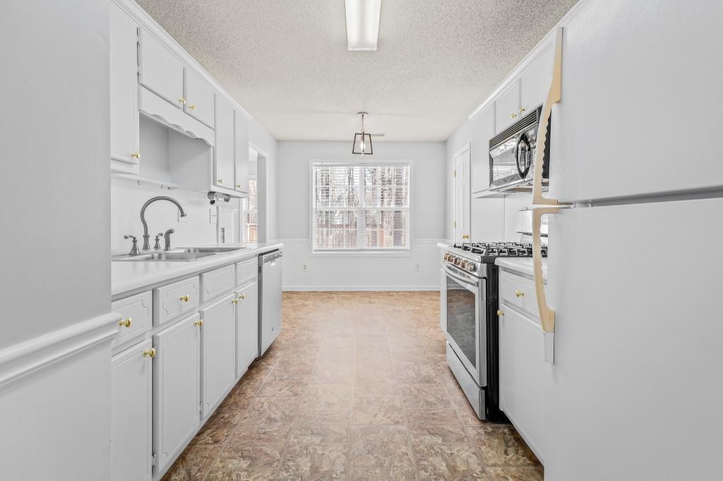 1707 Mountain Fort Way Dacula, GA 30019 - Photo 14 of 34 a kitchen with granite countertop a sink stove and refrigerator