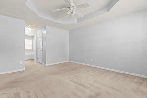 an empty room with chandelier fan and windows