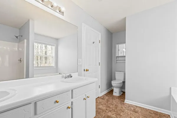 a spacious bathroom with a granite countertop sink a toilet and a shower